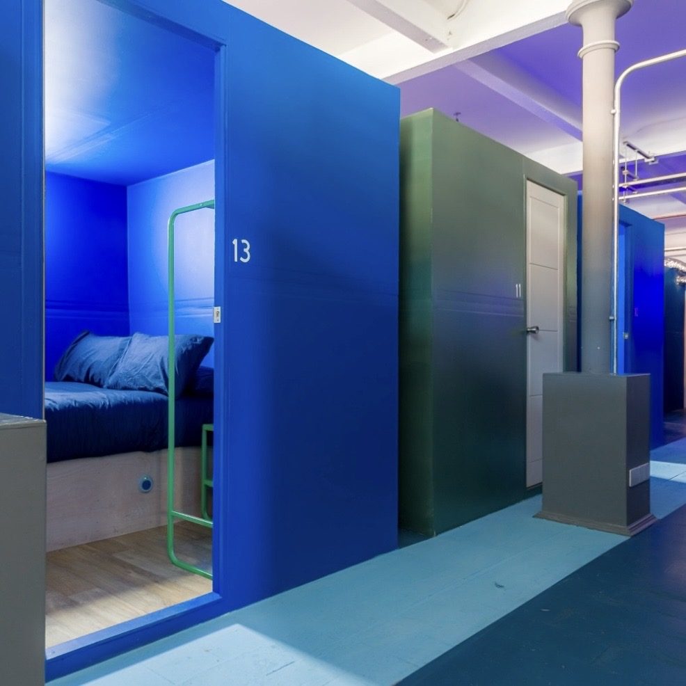 Blue and green sleep pods with numbered doors along the corridor