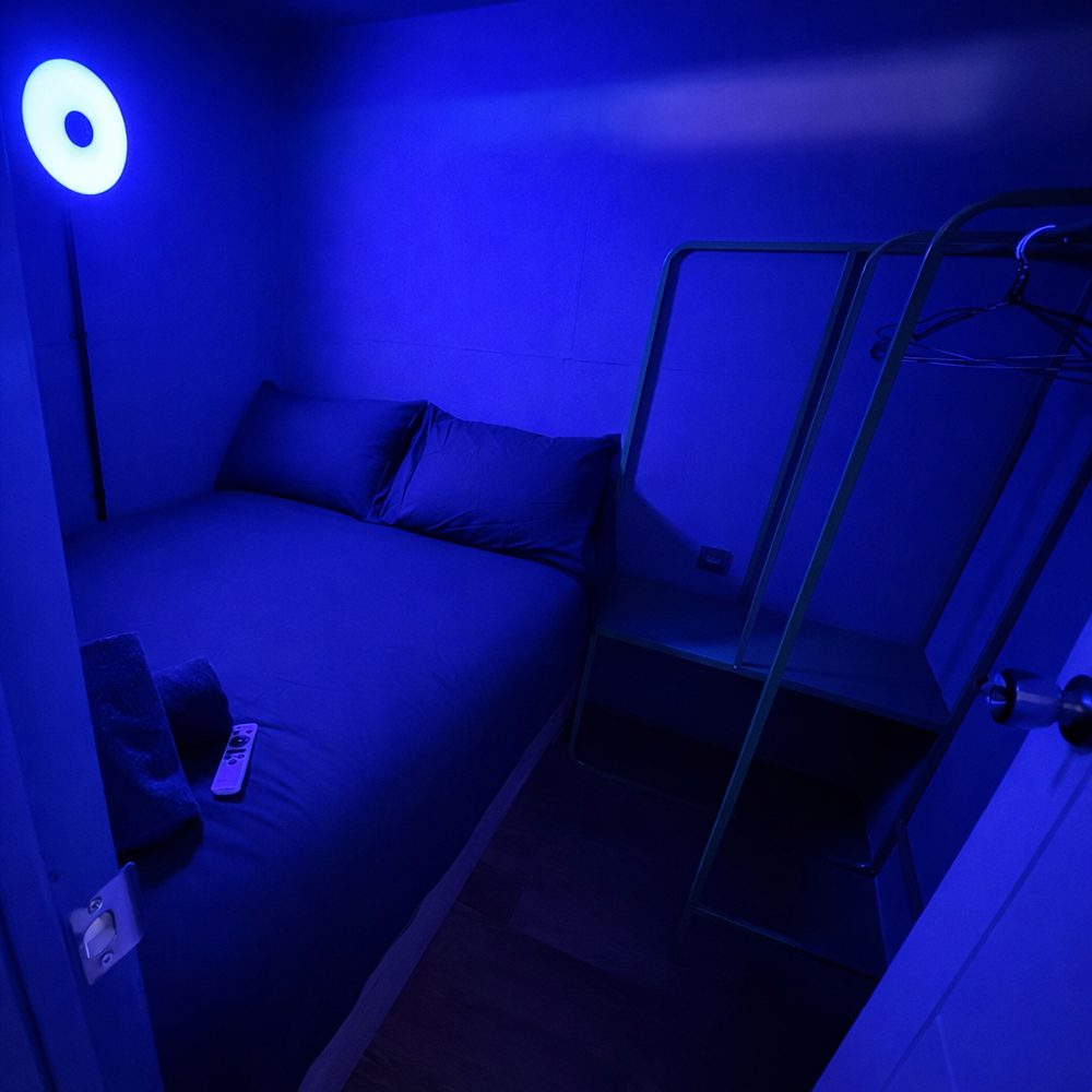 Inside one of our sleep pods, a double bed under blue light